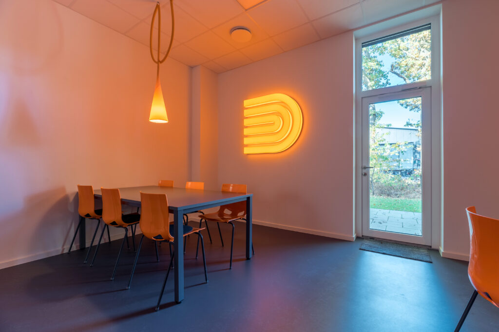 Unser Aufenthaltsraum mit warmen Akzenten in Orange - ein Ort für Teamgespräche, Pausen und neue Ideen