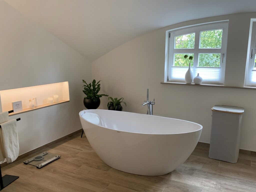 Modernes Badezimmer mit freistehender Badewanne, dekorativen Elementen und stimmungsvollem Lichteinfall